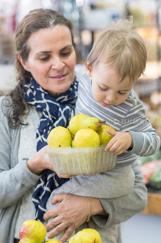 成熟的女人买水果和她的儿子