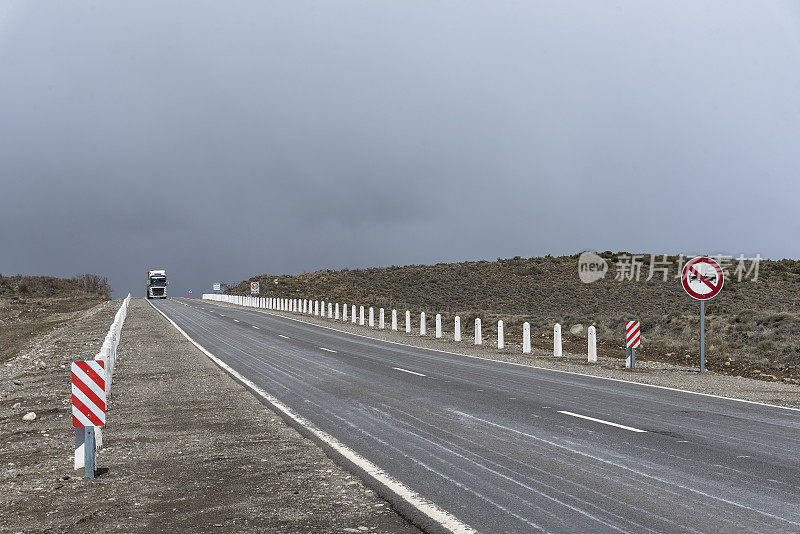 卡车行驶在双向高速公路，没有越界标志和速度限制，在阴天