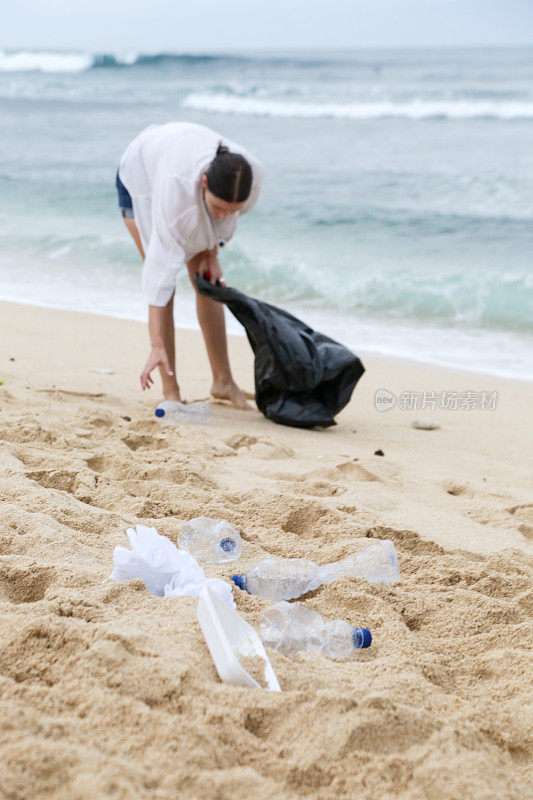 在海滩上捡垃圾的志愿者。Trash-free海域概念。一次性塑料是人类的嗜好，正在破坏我们的星球