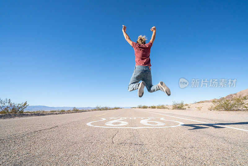 快乐的男人在公路中间跳得很高，男人在美国公路上跳——66号公路