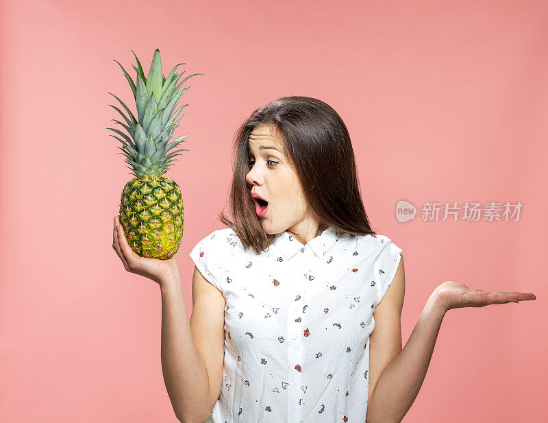 一个年轻的女人拿着一个成熟的菠萝