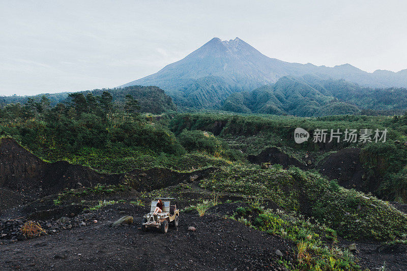 鸟瞰图上的女人坐在老式SUV上的背景默拉皮火山