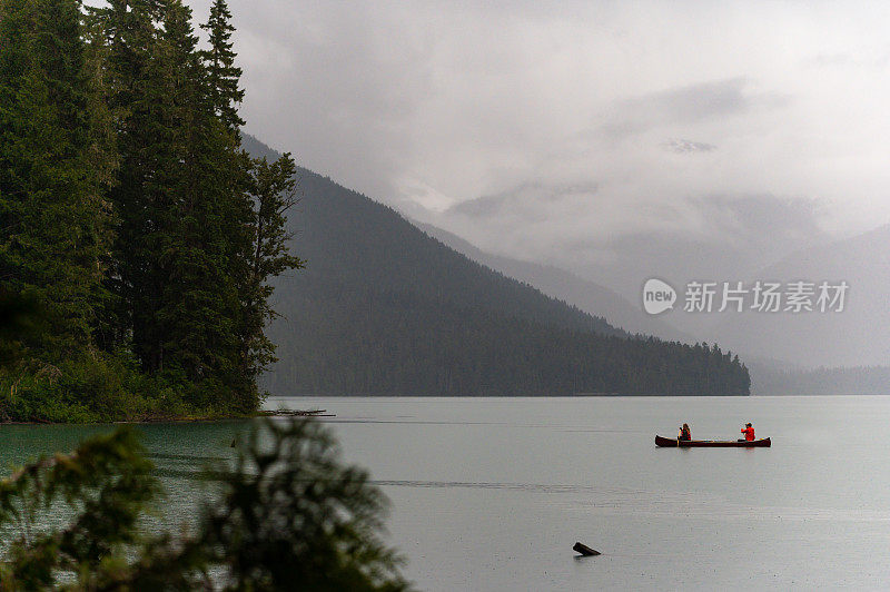远处一对夫妇在湖上划独木舟