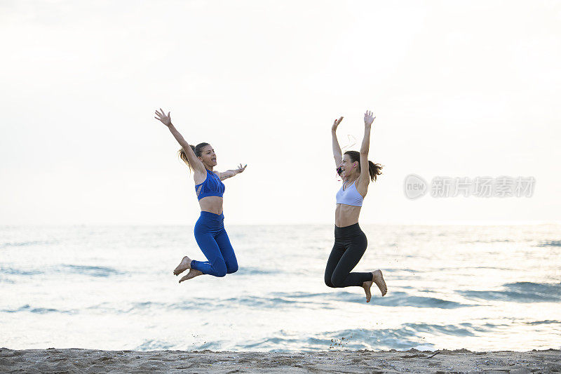 两个女性朋友在沙滩上跑步。