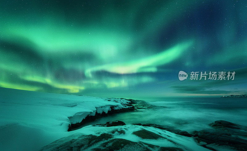 海洋上空的北极光。俄罗斯捷里别尔卡的北极光。星空，极地的光和云。夜冬山水以极光，海与石在模糊的水，雪山。旅行