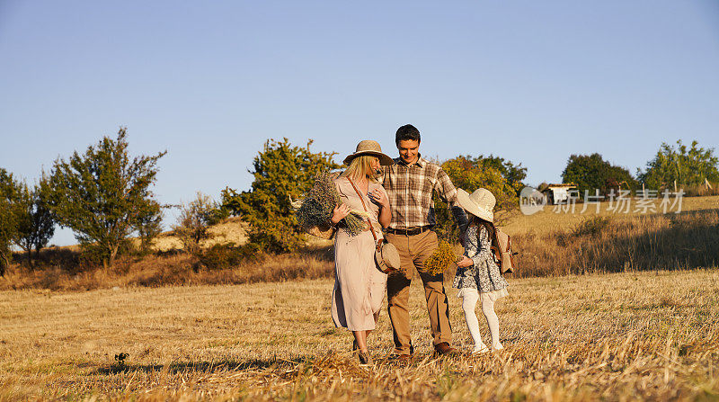 幸福的家庭:母亲，父亲，孩子，女儿对自然的秋天日落。秋日一家人在乡间散步