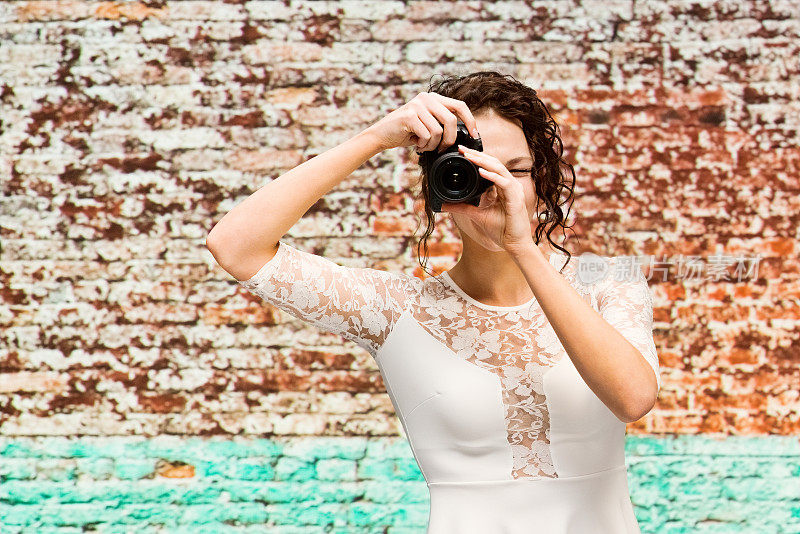 白人年轻女性摄影师穿着裙子和拿着相机