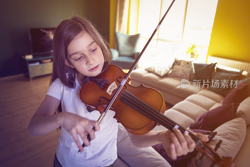 可爱的小女孩在家里拉小提琴