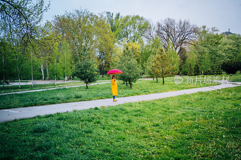 一个女人撑着一把红伞在雨中行走