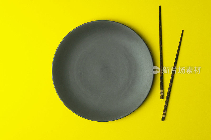 黄色背景上的空盘子。用中国筷子为亚洲菜和中国菜空盘子