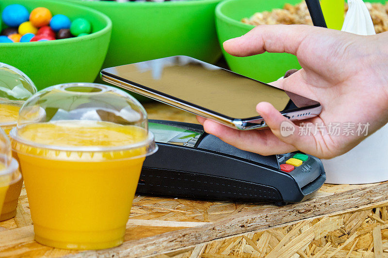 一个人用手机上的非接触式NFC系统来支付食物