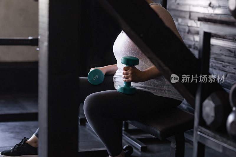 匿名超重女子在健身房用哑铃锻炼