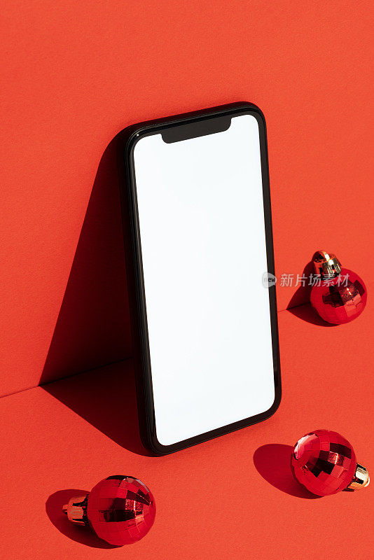 空白白屏幕智能手机模型，红色背景与圣诞球模板