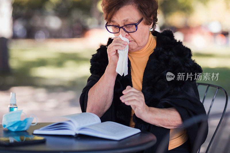 老奶奶坐在外面，擦着鼻子