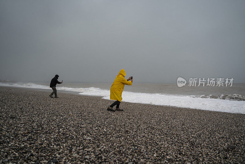 土耳其安塔利亚的一个雨天，两名男子在海滩上拍照