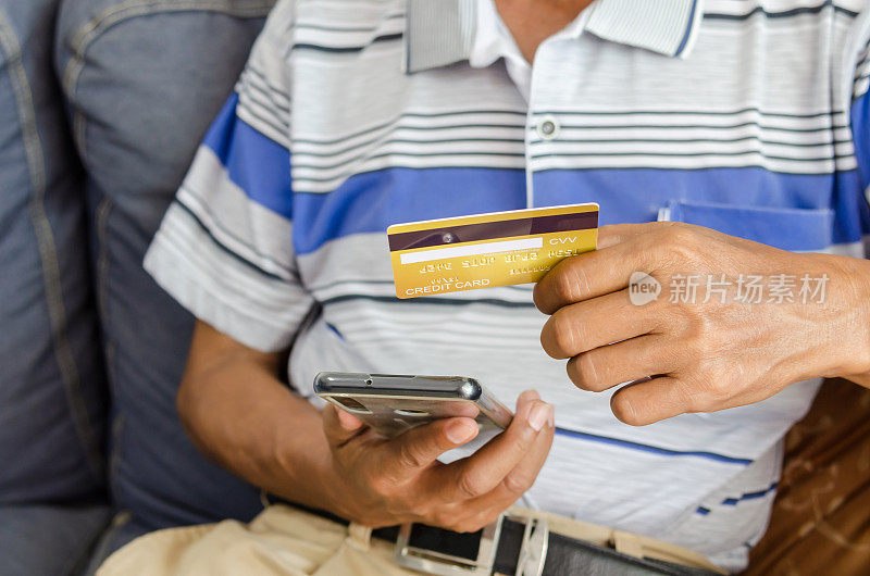 老年人看信用卡和手机。