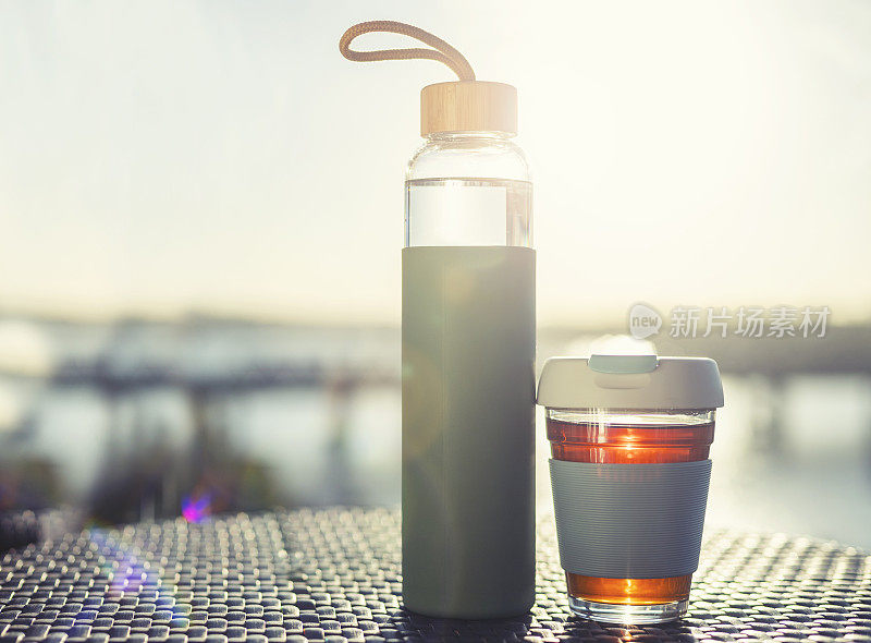 玻璃可重复使用的杯子和水瓶在阳光下。