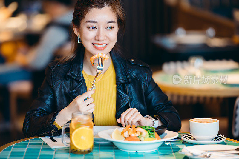 年轻的亚洲年轻女子在餐厅享受新鲜食物的肖像。