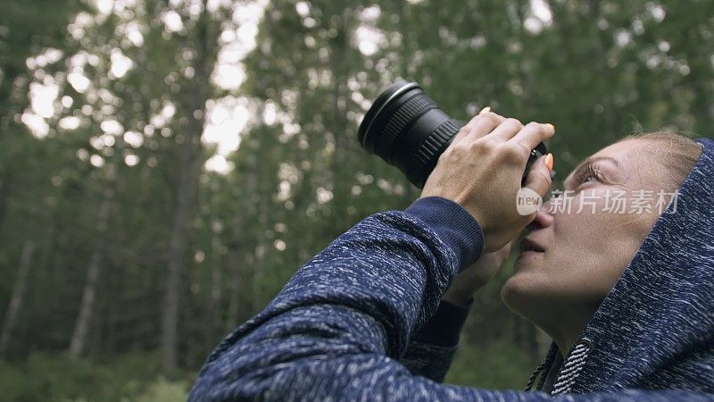 游客在森林中拍摄风景。一名白人女子近距离射击。女孩用无反光镜单反相机拍摄视频。