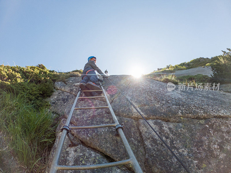 梯子上登山者的低角度视角，阳光