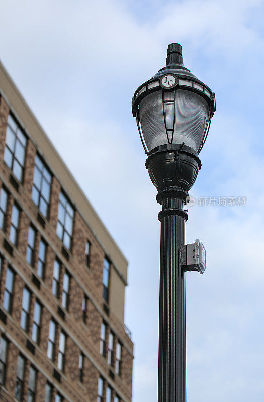 灯柱与JC泽西城的标志在顶部和高大的高层公寓楼的背景。