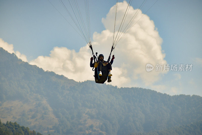 一个年轻人在山上和教练一起驾驶滑翔伞