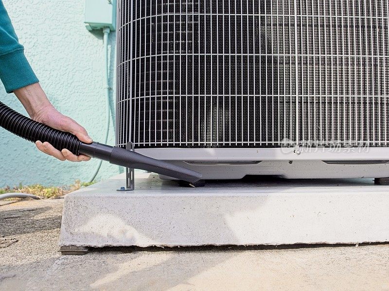 美国佛罗里达州墨尔本，房主在热泵周围吸尘，以确保HVAC系统的最高效率