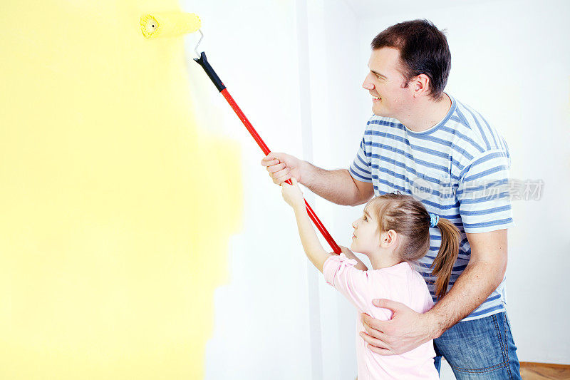 父亲和女儿在刷墙。