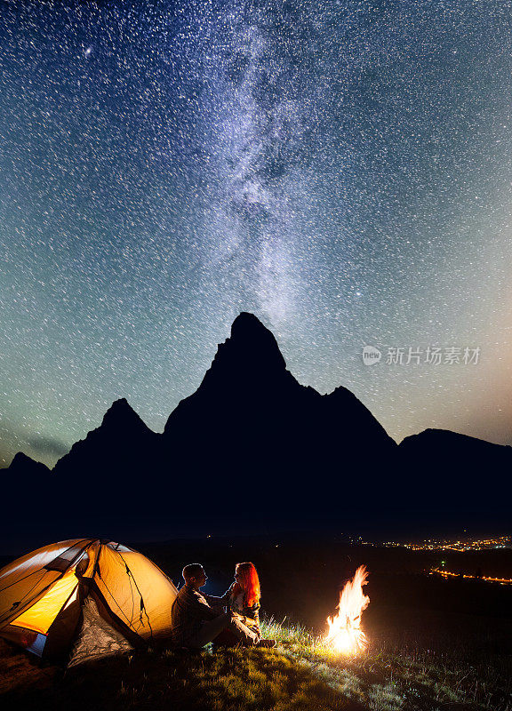 游客坐在篝火旁，在夜空下闪耀着星光