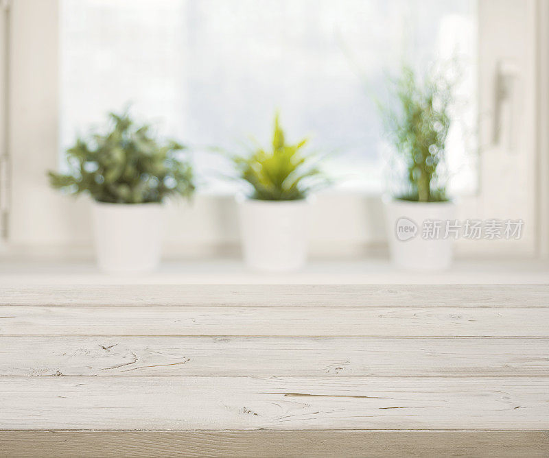 模糊的冬季窗户上的木桌，背景是花盆