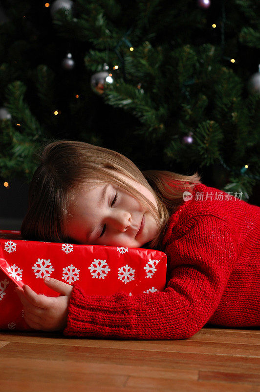 小女孩在圣诞树旁的圣诞礼物上熟睡