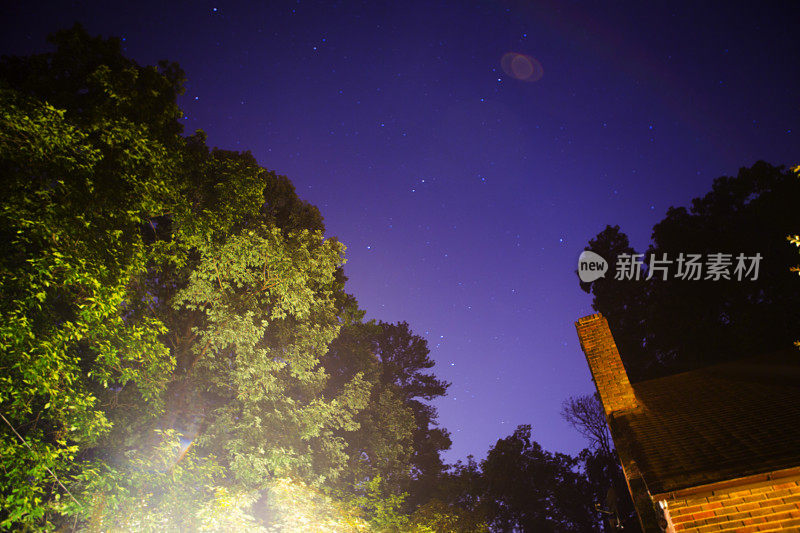 星星在夜晚的天空，在树和房子上面