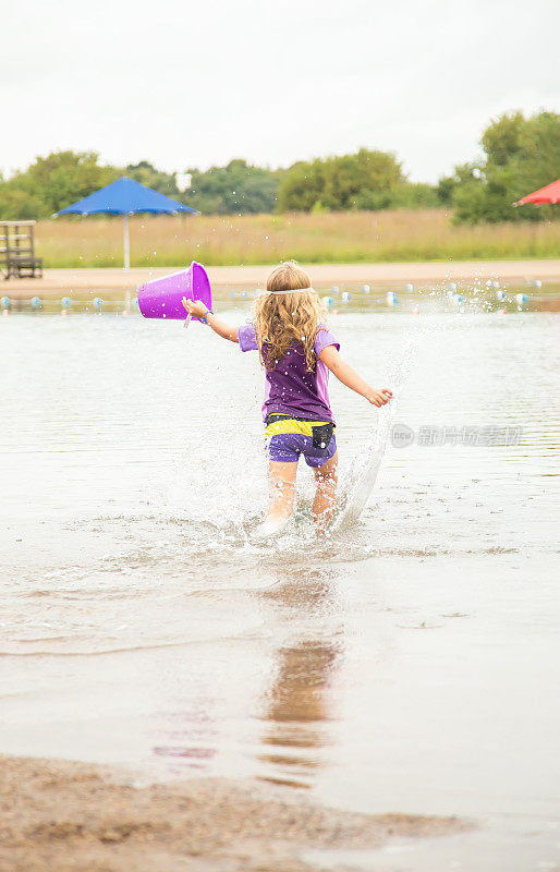 女孩拿着塑料桶跑进游泳池