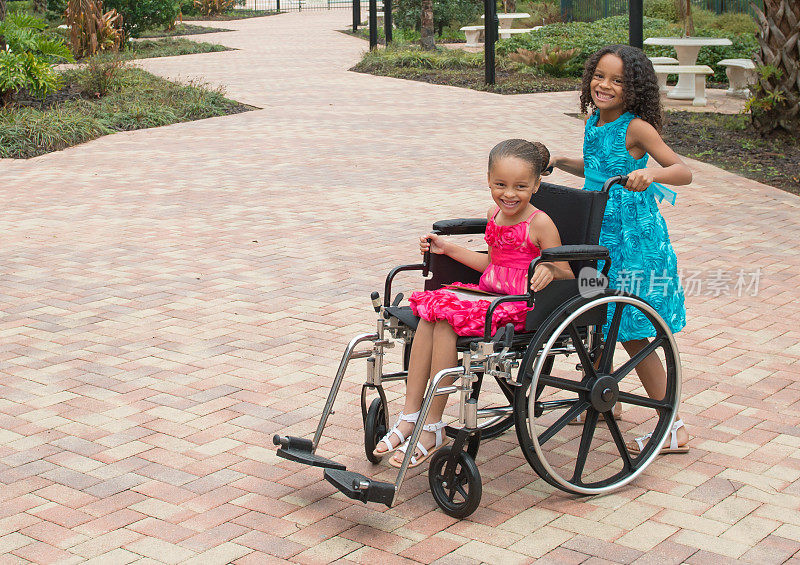 非裔美国女孩推着坐轮椅的妹妹