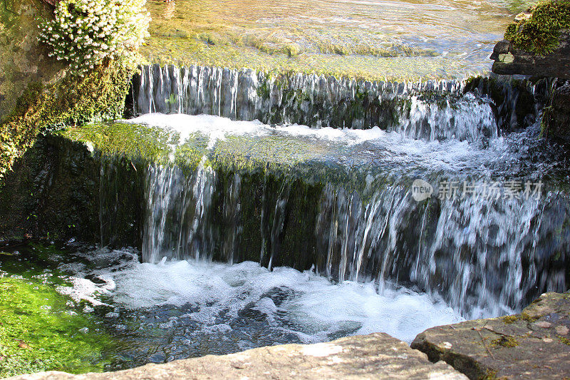瀑布特写图像，小溪流过岩石，景观假山花园