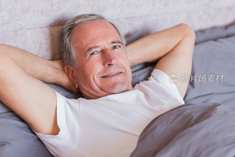 成熟的男人双手放在脑后，躺在床上休息