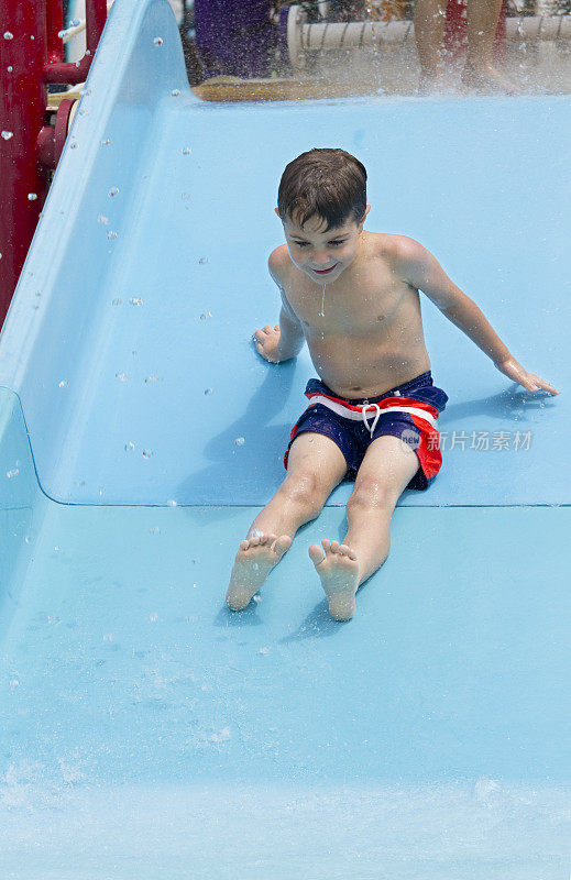 儿童(男孩)(5)在游泳池水上滑梯上游泳和玩耍
