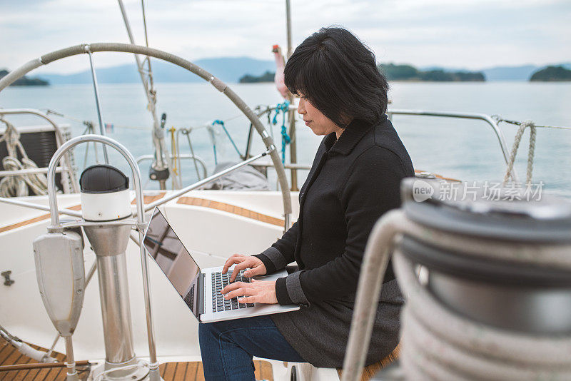 一个女人坐在游艇上用电脑