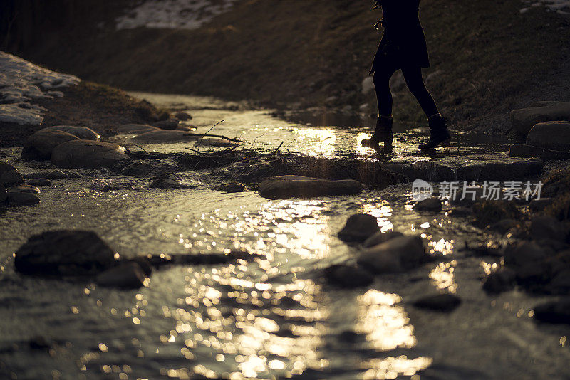 女人跨过小溪
年轻女子在小溪边