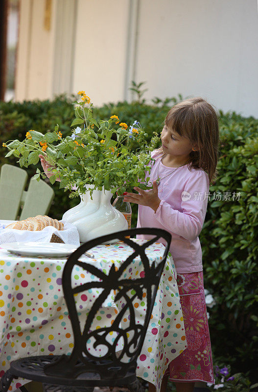 小女孩在外面帮忙摆餐桌。