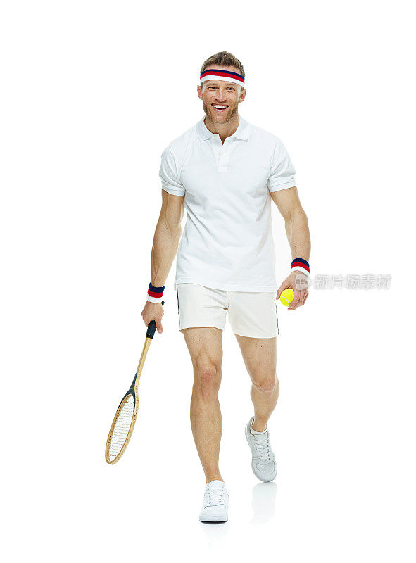 微笑的男子网球运动员拿着球和走路