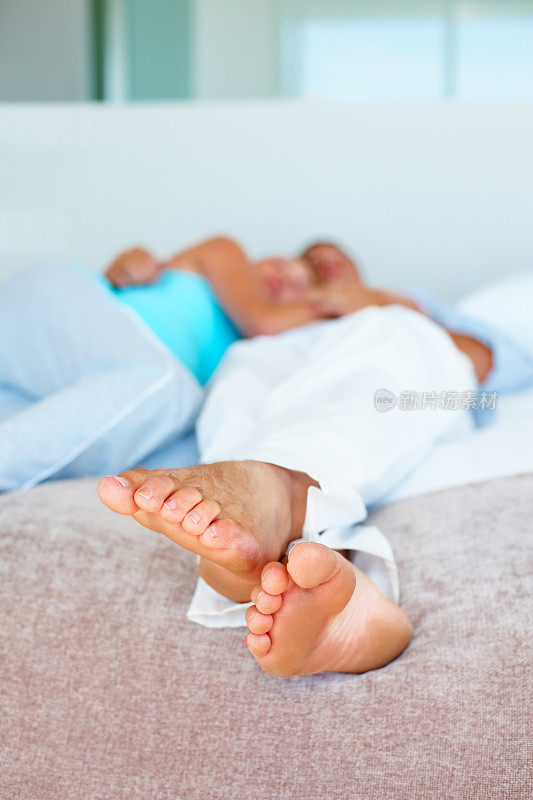 一对夫妻躺在床上，专注于男性的脚