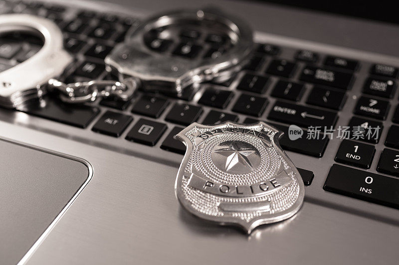 网络犯罪:手提电脑上的手铐和警徽。