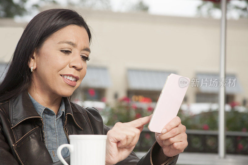 一个在户外咖啡店用手机的女人。