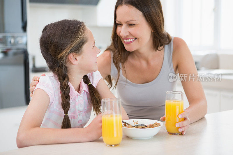 幸福的女人和女儿在厨房吃早餐