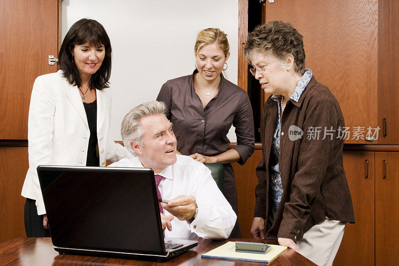 商务团队聚集在笔记本电脑周围