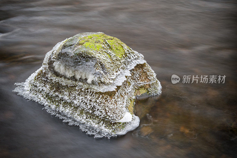 河中有霜冻、冰和苔藓的巨石