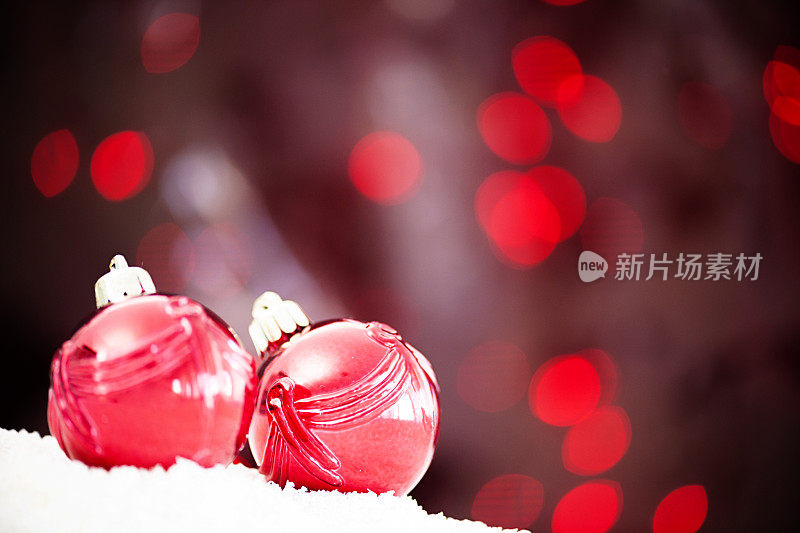 两件红色的圣诞装饰品，背景上有发光的斑点