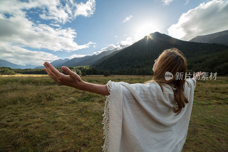 一个年轻女子的肖像在日出放松，双臂伸展