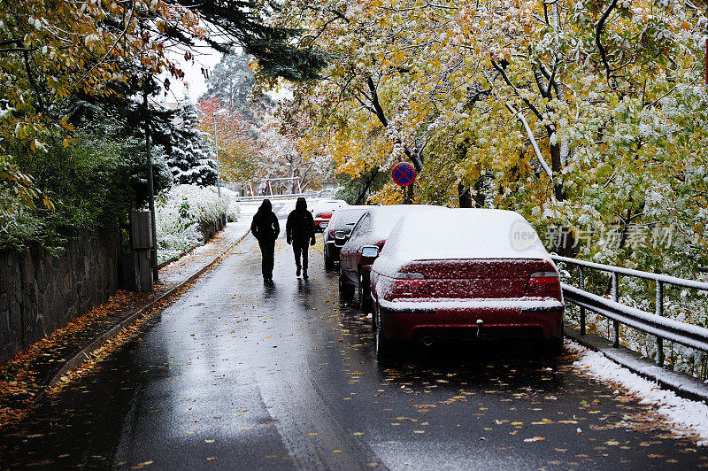 下雪的汽车停在秋天的城市里